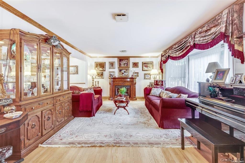 Living area with light wood-type flooring, a fireplace, and crown molding