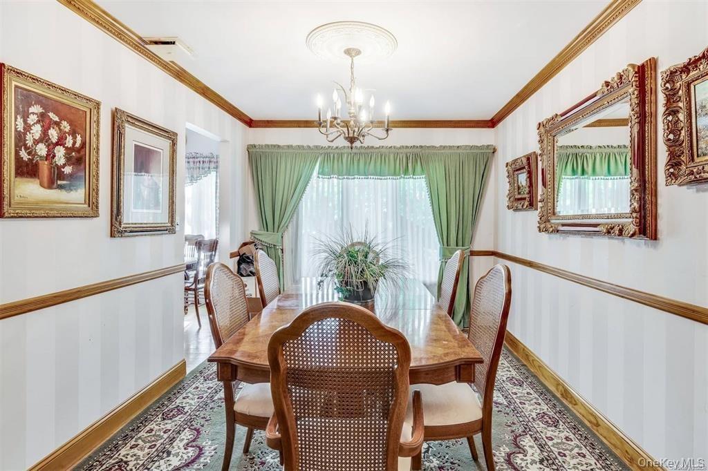 Dining area featuring plenty of natural light, crown molding, wallpapered walls, and a chandelier