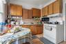 Kitchen featuring white range with gas stovetop, brown cabinets, light wood-style floors, black microwave, and backsplash