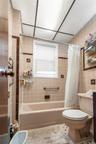 Bathroom featuring shower / bath combination with curtain, tile walls, and tile patterned flooring