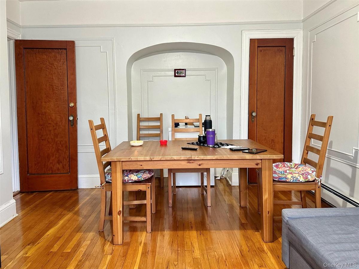 Dining room featuring hardwood / wood-style floors, a baseboard heating unit, and arched walkways