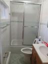 Bathroom featuring tile walls, vanity, light tile patterned floors, bath / shower combo with glass door, and a baseboard radiator