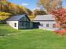 Back of house with a lawn, stone siding, a standing seam roof, and a metal roof