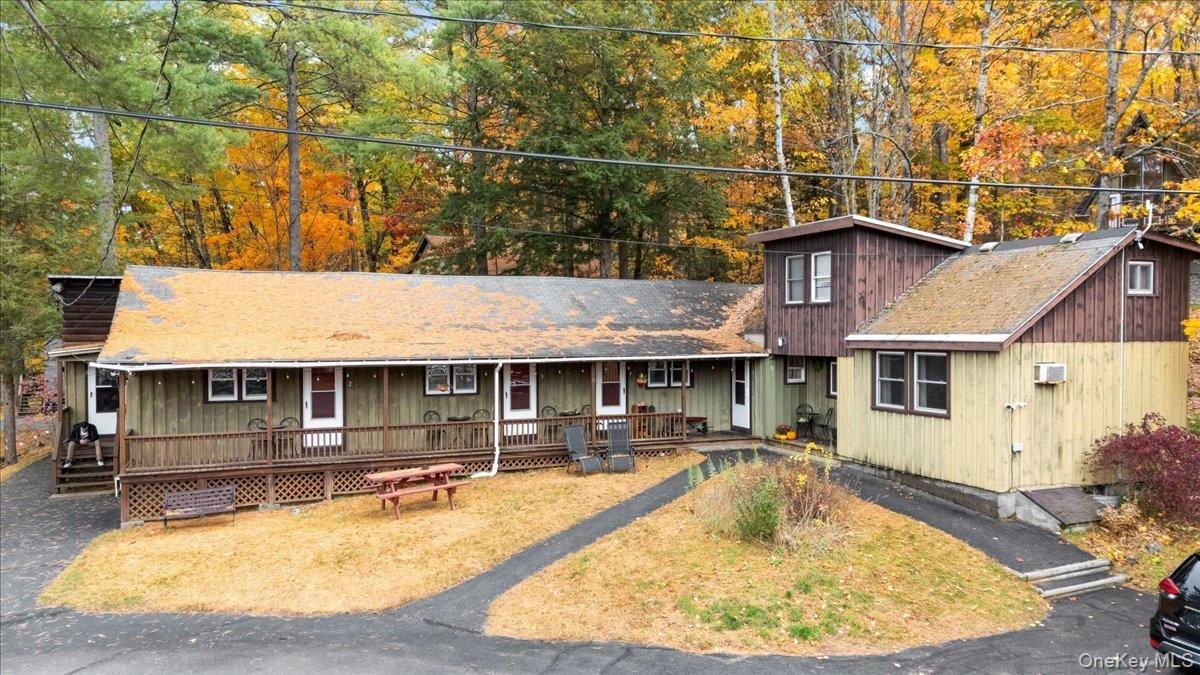 Rustic home with a porch, roof with shingles, and view of scattered trees