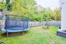 Fenced backyard with a trampoline and a playground
