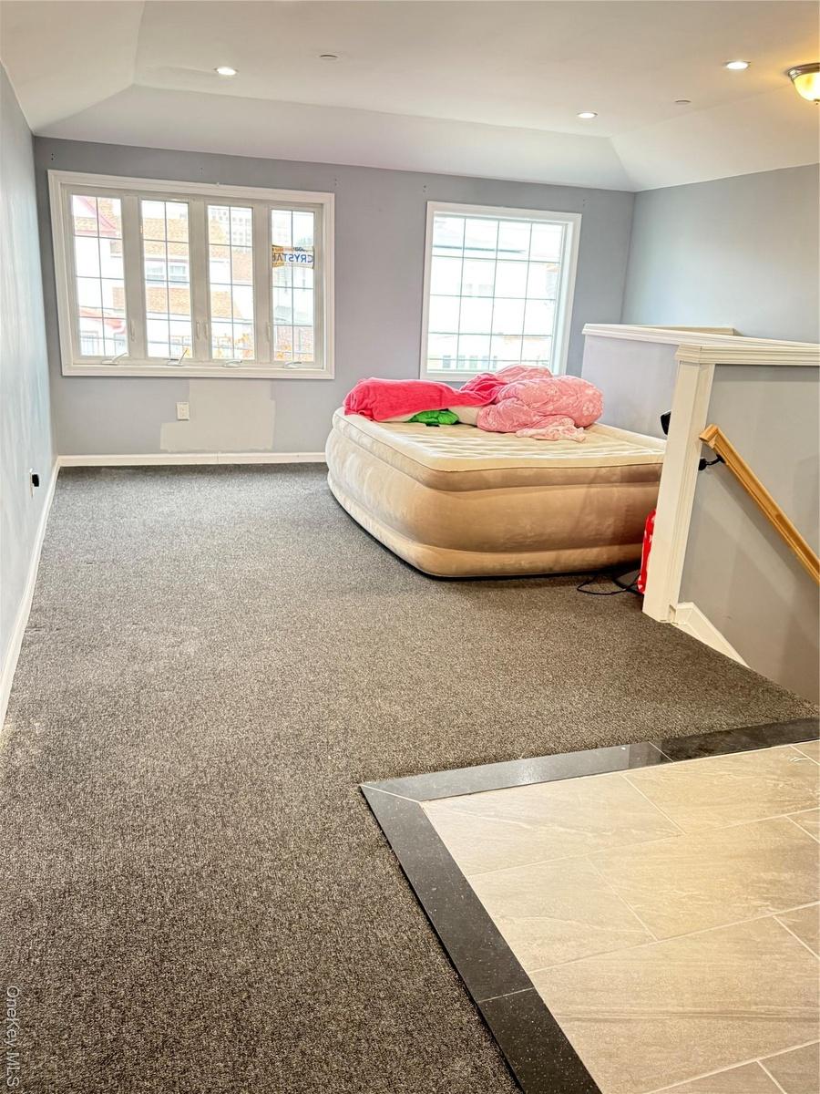 Bedroom with lofted ceiling, recessed lighting, and light colored carpet