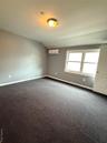 Spare room featuring dark colored carpet and lofted ceiling