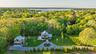 Aerial view of secluded property and surrounding area featuring wooded acreage and proximity to water