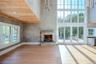 Open plan living room with a vaulted ceiling, stone fireplace, panoramic windows, wood ceiling and stucco walls
