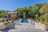 View of pool with a patio, view of scattered trees, and a wooden deck