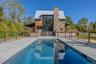 Swimming pool with a patio area and view of wooded area