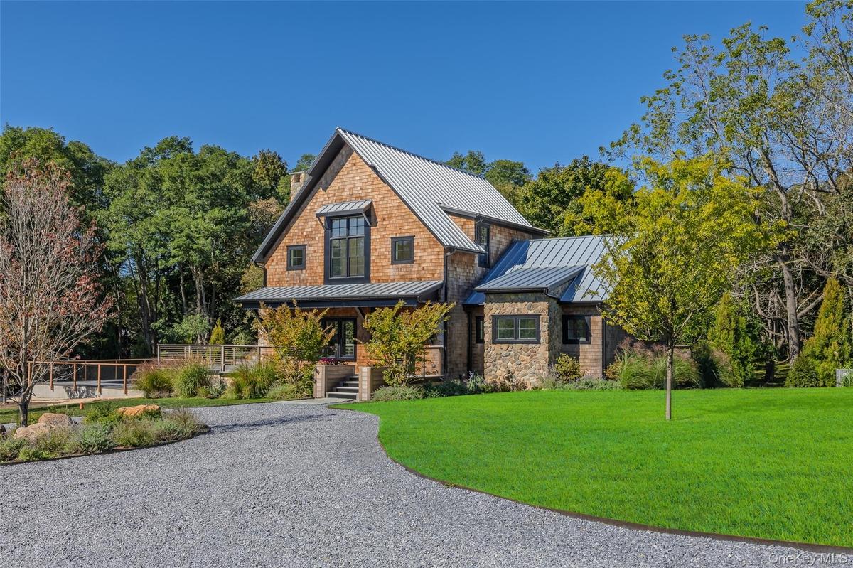 View of front of house with a standing seam roof, a metal roof, a front lawn, covered porch, and driveway