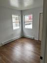 Spare room featuring plenty of natural light, dark wood-style floors, and a baseboard heating unit