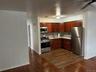 Kitchen featuring appliances with stainless steel finishes, light countertops, a ceiling fan, dark wood finished floors, and tasteful backsplash
