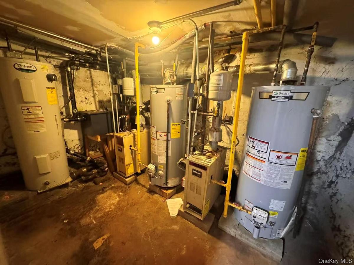 Utility room featuring gas water heater, water heater, and a heating unit