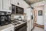 Kitchen with wallpapered walls, light tile patterned floors, light countertops, gas range oven, and white cabinets