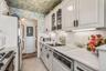 Kitchen with appliances with stainless steel finishes, light countertops, wallpapered walls, light tile patterned floors, and backsplash