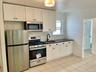 Kitchen featuring appliances with stainless steel finishes, decorative backsplash, white cabinetry, light tile patterned floors, and dark stone counte