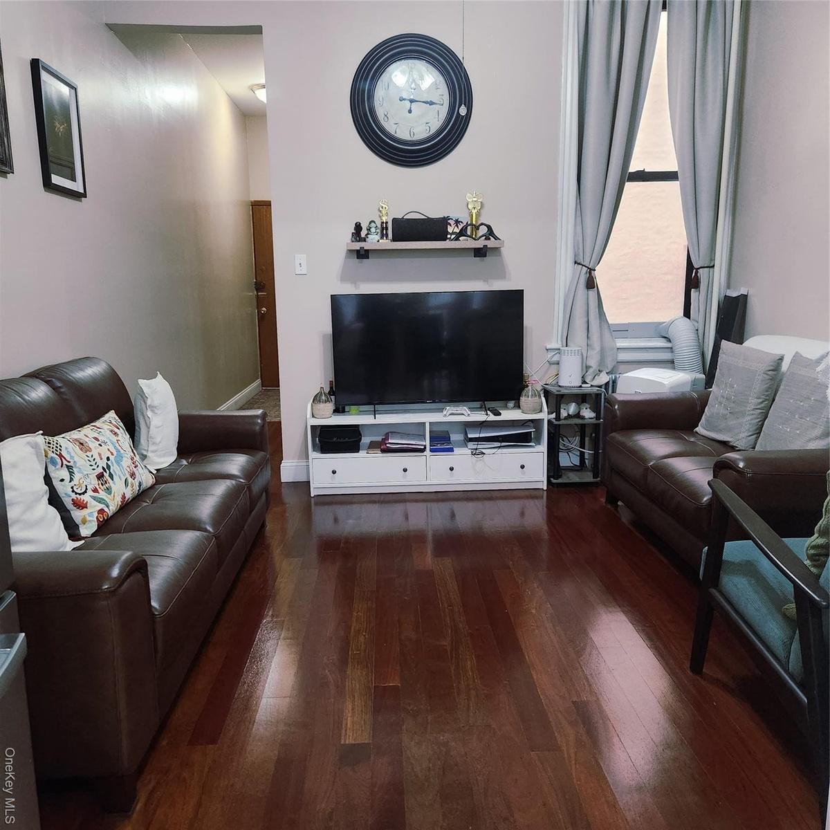 Living room featuring dark wood-style floors and baseboards
