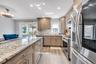 Kitchen featuring appliances with stainless steel finishes, light stone counters, tasteful backsplash, recessed lighting, and light wood-type flooring