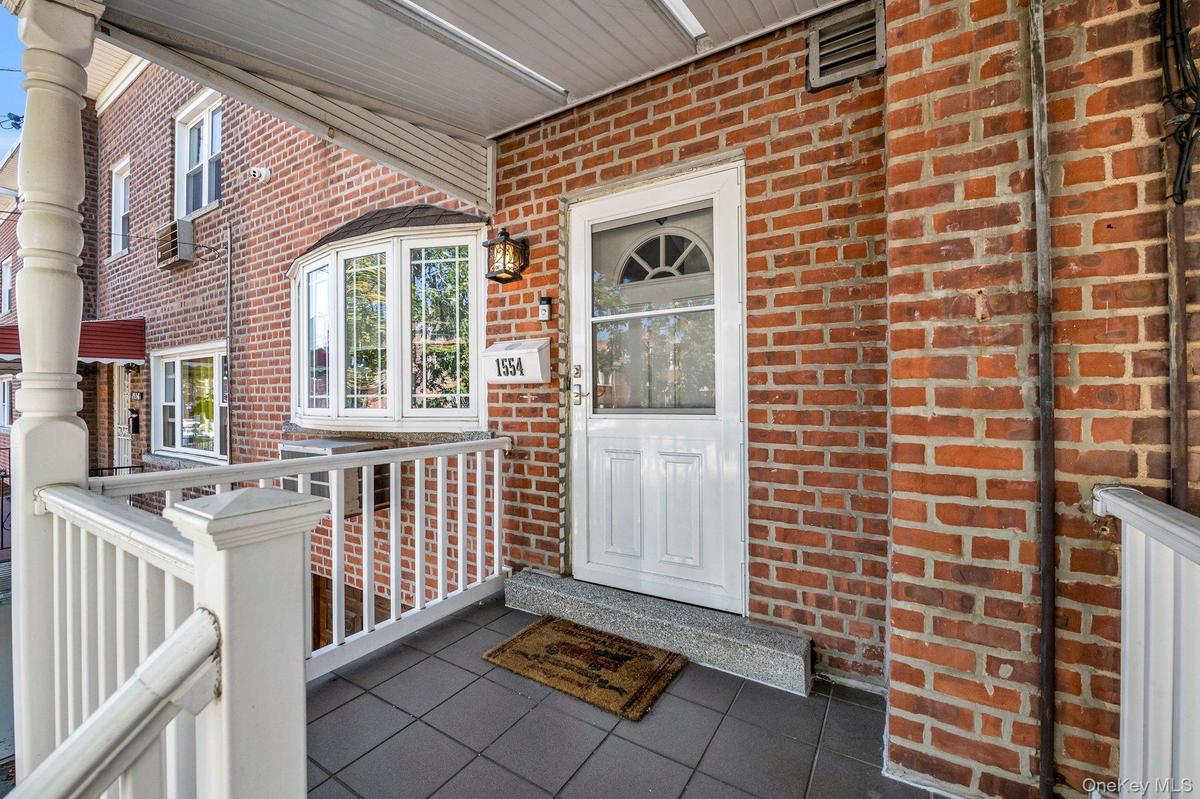 Entrance to property with covered porch and brick siding