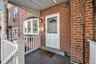 Entrance to property with covered porch and brick siding