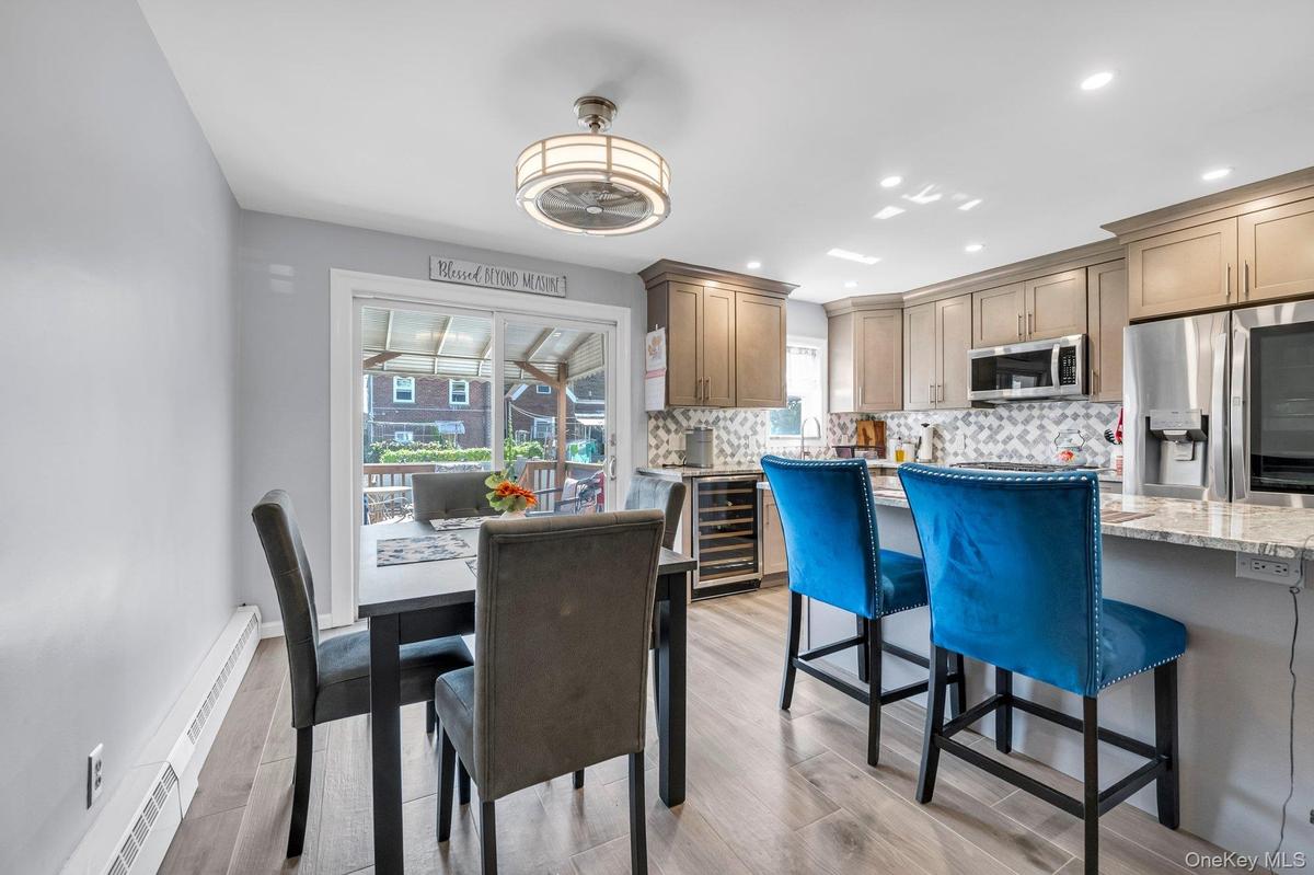 Dining area with light wood finished floors, recessed lighting, a baseboard heating unit, and wine cooler