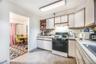 Kitchen with white appliances, white cabinetry, a baseboard radiator, and sink