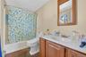 Full bath with shower / bath combo with shower curtain, vanity, a baseboard heating unit, and dark tile patterned flooring