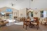 Dining room featuring lofted ceiling, carpet floors, a glass covered fireplace, and a ceiling fan