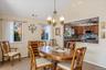 Dining room with a chandelier, light colored carpet, high vaulted ceiling, and a ceiling fan