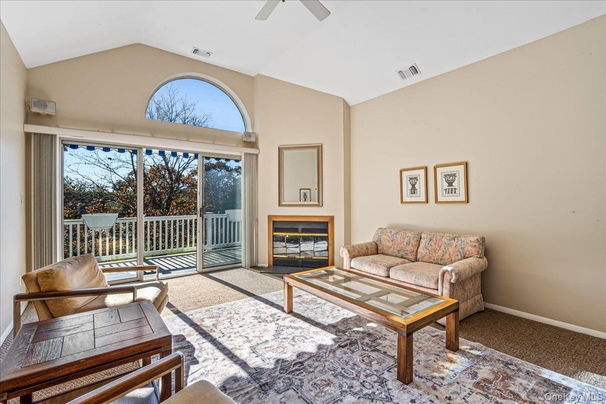 Living room featuring lofted ceiling, carpet floors, and a ceiling fan