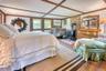 Bedroom featuring a wood stove, wood finished floors, a wall mounted air conditioner, and beamed ceiling
