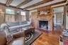 Living room with hardwood / wood-style flooring, beam ceiling, and a fireplace with flush hearth