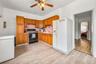 Kitchen with a ceiling fan, white fridge with ice dispenser, light countertops, light wood-style flooring, and black gas stove