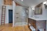 Full bathroom featuring light wood finished floors, vanity, a stall shower, and vaulted ceiling