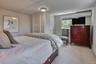 Bedroom with light colored carpet and an AC wall unit