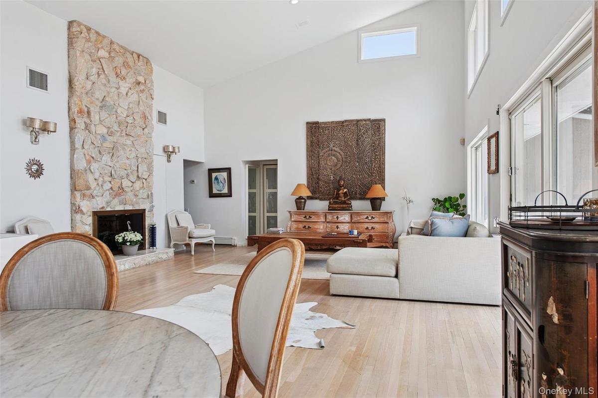 Living area with high vaulted ceiling, wood finished floors, and a stone fireplace