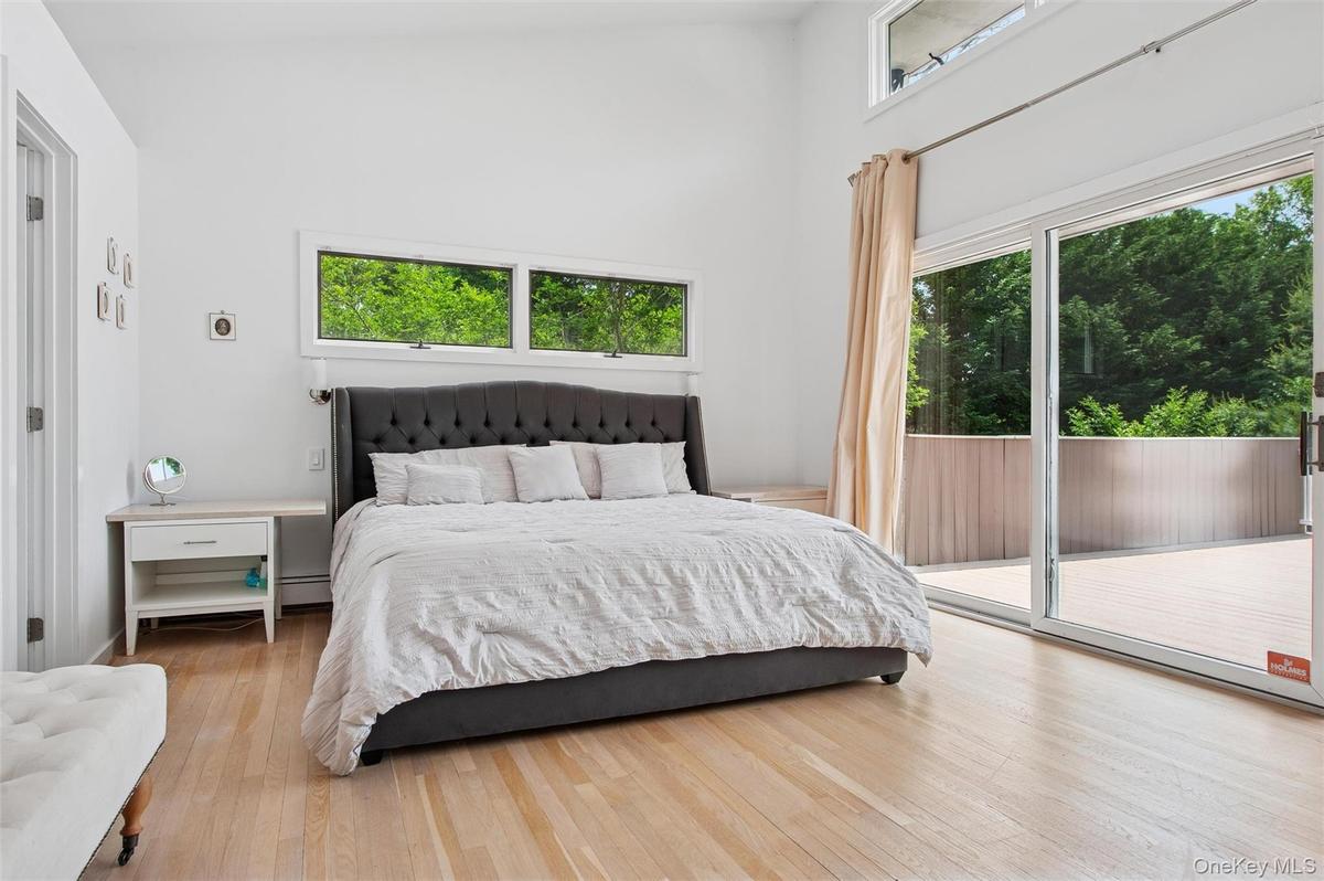 Bedroom featuring access to outside, wood finished floors, a high ceiling, and a baseboard heating unit