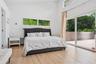 Bedroom featuring access to outside, wood finished floors, a high ceiling, and a baseboard heating unit