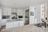 Kitchen with wall chimney exhaust hood, stainless steel appliances, light stone counters, and a sink
