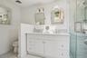 Bathroom featuring wainscoting, toilet, a shower stall, and double vanity