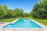View of pool featuring a patio area and view of wooded area