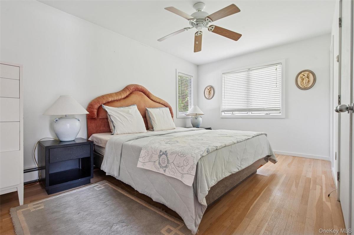 Bedroom featuring wood finished floors, a baseboard radiator, baseboards, and ceiling fan