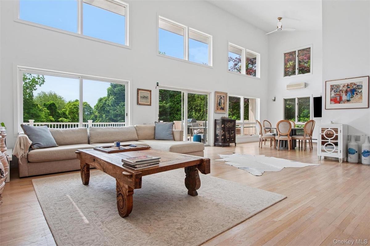 Living room featuring a high ceiling, light wood-type flooring, and a wall mounted air conditioner