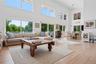 Living room featuring a high ceiling, light wood-type flooring, and a wall mounted air conditioner