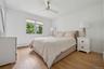 Bedroom with baseboard heating, light wood-style flooring, a ceiling fan, and baseboards
