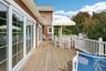 Expansive mahogany deck featuring an inviting outdoor dining area with seamless access through sliding glass doors.