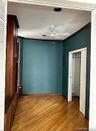 Empty room with wood finished floors, ceiling fan, and ornamental molding