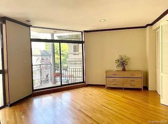 Sunlit living space featuring hardwood floors and oversized windows that fill the room with natural light. The open layout creates a comfortable setti